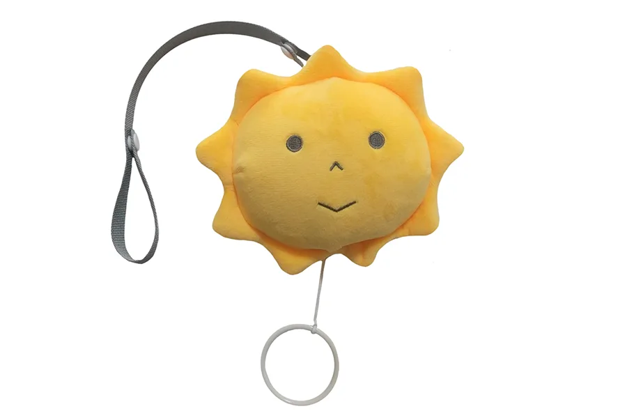 “小さな太陽シリーズ” いつもいっしょ。太陽の形のぬいぐるみに、グレーのストラップと、引くとオルゴールが鳴る白いリングが付いている（写真提供：株式会社トラーナ）